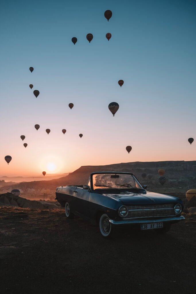 Lever de soleil entre une voiture de collection et les montgolfières. Photo de Johan Richomme.